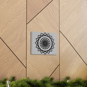 May include: A black and white geometric mandala design printed on a square canvas with a gray background.