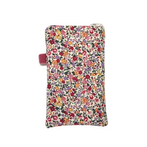 May include: A small white zippered pouch with a floral print in shades of red, pink, yellow, and purple. The pouch has a pink fabric tab.