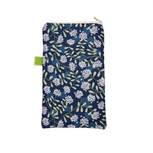 May include: A rectangular pouch with a floral design. The navy blue fabric features white flower clusters and green leaves. A small green tab is on the side. The zipper is silver.