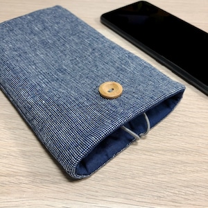 May include: A blue and white patterned phone case with a wooden button closure. The case is made of fabric and has a blue lining.