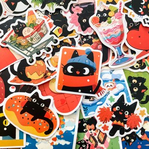 May include: A collection of colorful stickers featuring cartoon black cats in various poses and settings. Some stickers show cats with food, in winter attire, or as cheerleaders. The stickers have a white border and are set against a white background.