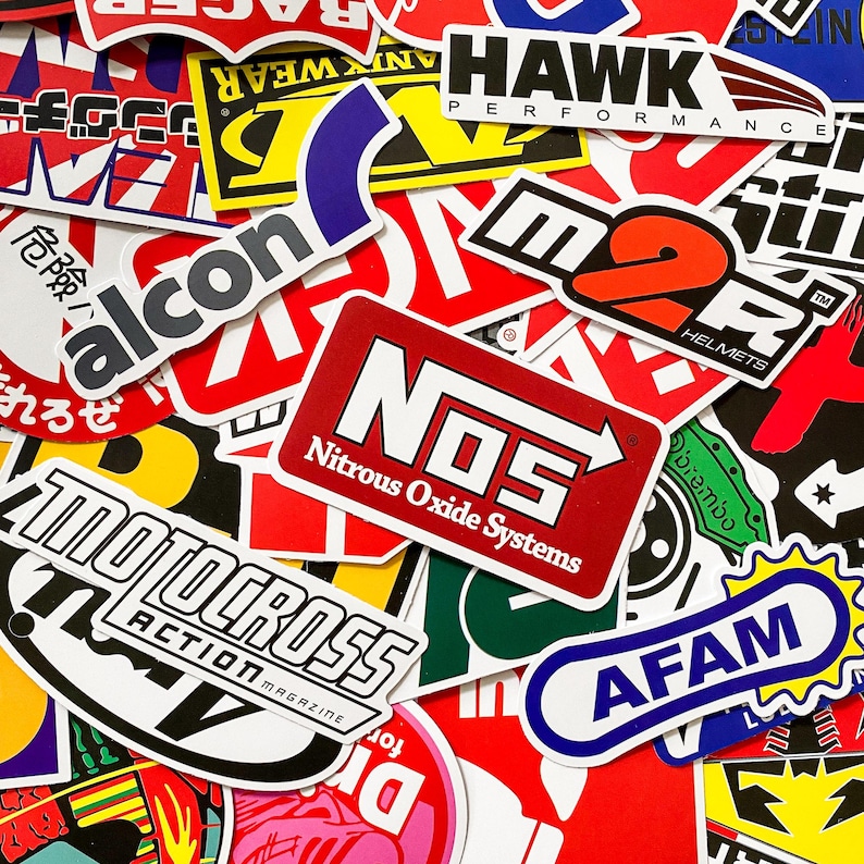 Pode incluir: Uma cole&ccedil;&atilde;o de autocolantes coloridos com v&aacute;rios logotipos e texto. Os autocolantes apresentam marcas como NOS Nitrous Oxide Systems, M2R Helmets e Motocross Action Magazine. Os autocolantes s&atilde;o vermelhos, brancos, azuis, amarelos e pretos.
