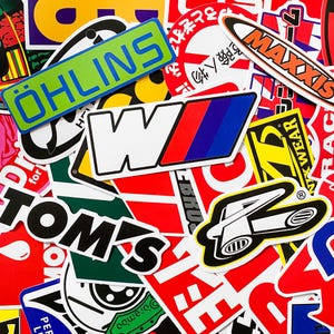 Pode incluir: Uma cole&ccedil;&atilde;o de autocolantes coloridos com v&aacute;rios log&oacute;tipos e texto. Os autocolantes apresentam marcas como Ohlins, Maxxis e Tom's. Os autocolantes t&ecirc;m v&aacute;rias formas e tamanhos, com uma mistura de texto e designs gr&aacute;ficos.
