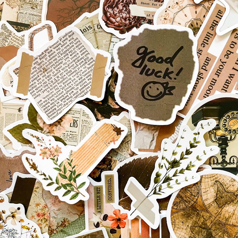 May include: A collection of vintage-style stickers and ephemera in shades of brown, beige, and green. The stickers feature botanical illustrations, newspaper clippings, and handwritten text, including "Good luck!" and a smiley face.
