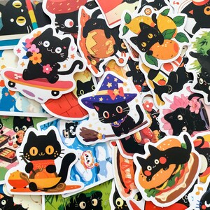 May include: A collection of colorful stickers featuring black cats in various poses. Some cats are on skateboards, wearing witch hats, or holding food. The stickers have a cartoon style with bright colors and playful designs.