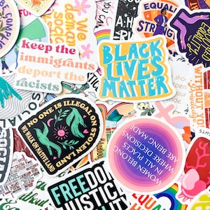 May include: A collection of colorful stickers with various social justice and equality-themed messages. The stickers feature phrases like "Black Lives Matter," "No one is illegal on stolen land," and "Freedom Justice Equality." The designs include illustrations and text.