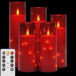 以下が含まれることがあります： 透明なガラスシリンダーに入った、5つの赤いLEDピラーキャンドルのセット。各キャンドルはちらつきのある黄色の炎を持ち、小さな温白色のライトで包まれています。リモコンが写っています。
