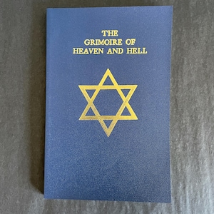 May include: A blue book with gold lettering and a gold Star of David. The text on the cover reads "THE GRIMOIRE OF HEAVEN AND HELL". The book is rectangular and has a textured surface.