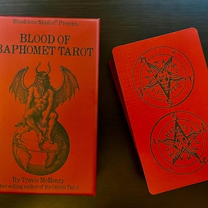 May include: A red Blood of Baphomet Tarot deck box and a matching card back. The box features black text reading Bloodstone Studios Presents, Blood of Baphomet Tarot, By Travis McHenry, and Best-selling author of the Occult Tarot with a winged figure.