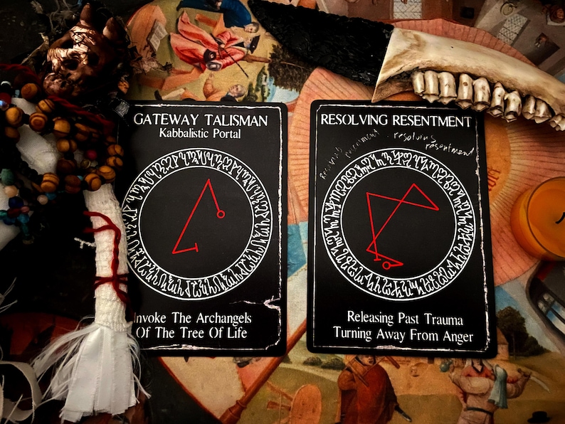 May include: Two black cards with white text and red symbols. The card on the left says "Gateway Talisman Kabbalistic Portal" and the card on the right says "Resolving Resentment".