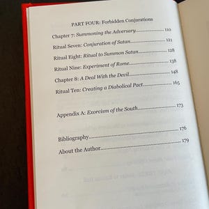 May include: An open book with a red spine showing a table of contents page titled PART FOUR: Forbidden Conjurations. The list includes Chapter 7: Summoning the Adversary, Ritual Seven: Conjuration of Satan, Ritual Eight: Ritual to Summon Satan, Ritual Nine: Experiment of Rome, Chapter 8: A Deal With the Devil, Ritual Ten: Creating a Diabolical Pact, Appendix A: Exorcism of the South, Bibliography, and About the Author.