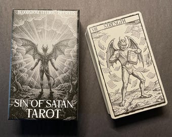 May include: A deck of Sin of Satan Tarot cards by Bloodstone Studios. The box features a winged figure standing in a landscape with the title text. The top card shows a winged figure holding a book titled Biblia Sacra with the text VIII Strength.