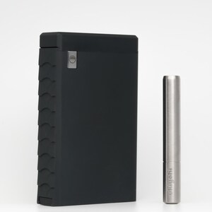 May include: A black, textured, rectangular case with a silver button on the front. Next to it is a silver metal tool with the word "wryeh" engraved on it.