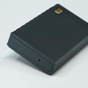 May include: A dark gray rectangular battery pack with a gold accent on the top. The battery pack has the word "remarkable" printed on the side.