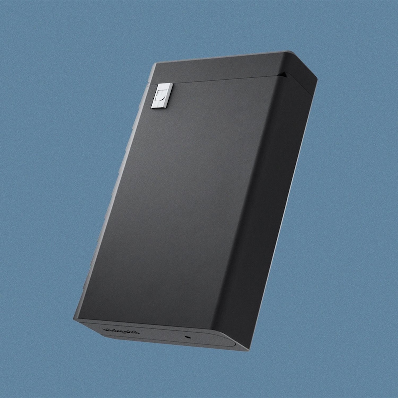May include: A black rectangular box with a small silver button on the top. The box has a slightly rounded edge and the word "Panga" is printed on the bottom.