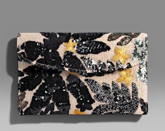 Può includere: Una pochette rettangolare con base in tessuto beige caratterizzata da un motivo ricamato di foglie di paillettes nere, accenti di paillettes argentate e piccole paillettes a forma di stella gialla sulla patta frontale e sul corpo principale.