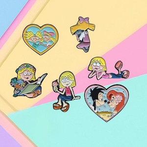 May include: Set of nine enamel pins featuring cartoon characters from popular animated television shows. The pins are colorful and feature characters like Doug,  Ren & Stimpy, and  Goofy.