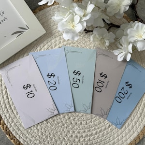 Puede incluir: Cinco vales de regalo con valores de 10, 20, 50, 100 y 200 dólares, dispuestos en forma de abanico. Cada vale tiene un borde decorativo y la palabra "Placeholder". Un marco con el texto "it's time to bloom" está en el fondo.