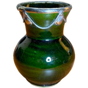 May include: A dark green ceramic vase with a glossy finish. The vase has a silver-colored rim and decorative accents. The vase has a bulbous body and a narrow neck, suitable for displaying flowers or as a decorative piece.