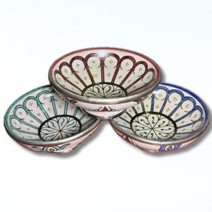 May include: Three decorative ceramic bowls with intricate floral patterns. The bowls feature a mix of colors, including pink, blue, and green, with silver rims. The designs are symmetrical and detailed, perfect for serving or display.