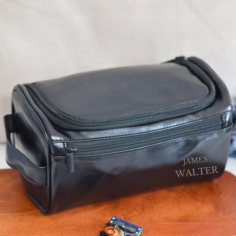 May include: Black leather travel toiletry bag with a zipper closure and a handle. The bag has the name "JAMES WALTER" embossed on the front.