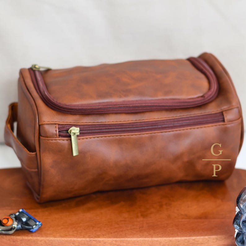 May include: A brown leather travel bag with a zipper closure and a gold zipper pull. The bag has a monogrammed "G/P" on the side.