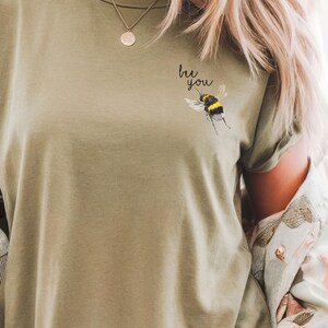 May include: A green t-shirt with the text "be you" and a bee graphic on the front.