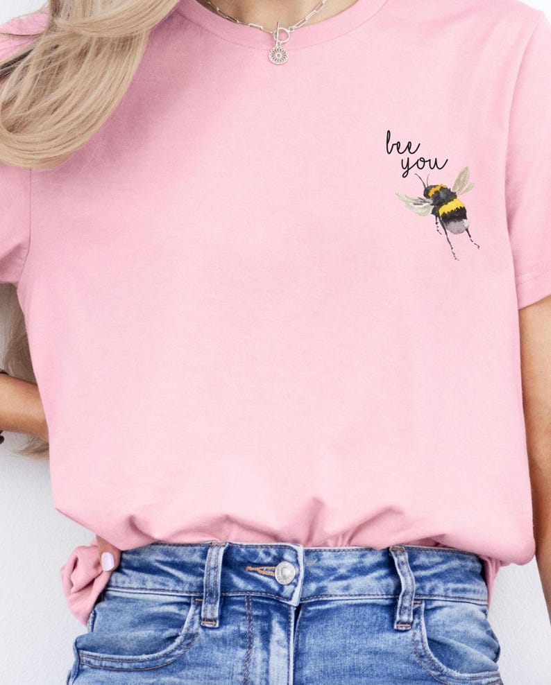 May include: A pink t-shirt with a bee graphic and the text "bee you" printed on the front.