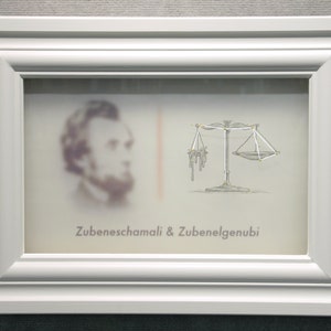 May include: A white frame with a black and white image of a person's face and a drawing of a scale with the text "Zubenelgenubi & Zubeneschamali" below the image.