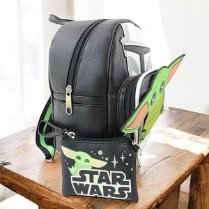 Puede incluir: Mochila negra con dise&ntilde;o de casco mandaloriano, una peque&ntilde;a bolsa verde de Baby Yoda y un accesorio a juego con forma de Baby Yoda. La bolsa presenta el logotipo de Star Wars y un gr&aacute;fico de Baby Yoda.