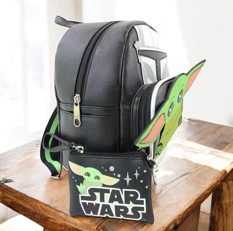 Puede incluir: Mochila negra con dise&ntilde;o de casco mandaloriano, una peque&ntilde;a bolsa verde de Baby Yoda y un accesorio a juego con forma de Baby Yoda. La bolsa presenta el logotipo de Star Wars y un gr&aacute;fico de Baby Yoda.