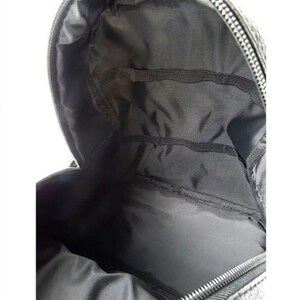 Puede incluir: Vista interior de una mochila negra. El interior cuenta con m&uacute;ltiples compartimentos y bolsillos, con cierre de cremallera. El forro es de tela gris oscuro. La mochila est&aacute; dise&ntilde;ada para transportar objetos.