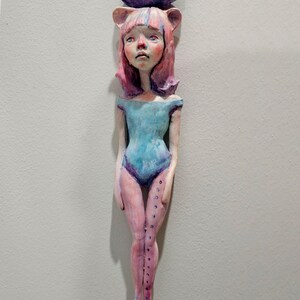May include: A handmade doll with pink hair and a blue leotard. The doll is holding a purple rock above its head that says "You Know Talent".