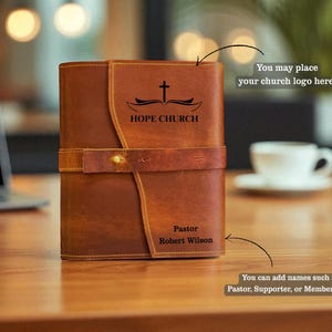 K&ouml;nnte beinhalten: Ein brauner Leder-Bibelumschlag mit Klappenverschluss und Riemen. Auf dem Umschlag stehen die Worte "HOPE CHURCH" und ein Kreuzsymbol. Der Text "Pastor Robert Wilson" ist ebenfalls sichtbar.