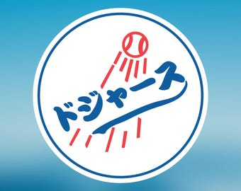May include: A circular logo featuring a baseball and Japanese text in blue and red. The logo shows a baseball with red lines radiating from it, and the Japanese text is in a stylized font. The logo is set against a white background with a blue border.