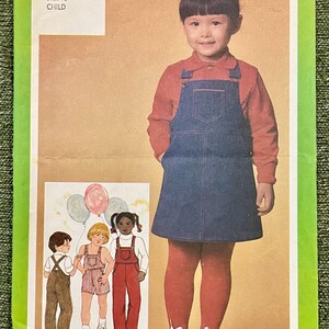 Op de afbeelding: Vintage Simplicity patroon 9722 voor een kinderoutfit. De afbeelding toont een meisje in een spijkerbroekjurk, rode panty's en schoenen. Het patroon bevat illustraties van verschillende outfit-varianten. De prijs is $1,75.