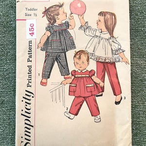 Può includere: Modello stampato Simplicity vintage per abbigliamento per bambini piccoli, con illustrazioni di tre bambini in diversi outfit. Il modello include un completo a quadretti, una camicetta bianca con pantaloni rossi e un completo rosso. Il numero del modello è 3725.