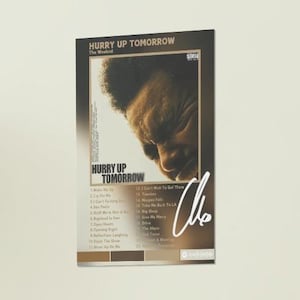 Può includere: Una copertina di album marrone e dorata con il titolo "Hurry Up Tomorrow" di The Weeknd. La copertina presenta un primo piano del viso di The Weeknd, con gli occhi chiusi e la testa inclinata verso il basso. La tracklist dell'album è stampata sul lato destro della copertina, e il titolo dell'album è stampato in grandi caratteri grassetto nella parte superiore della copertina.