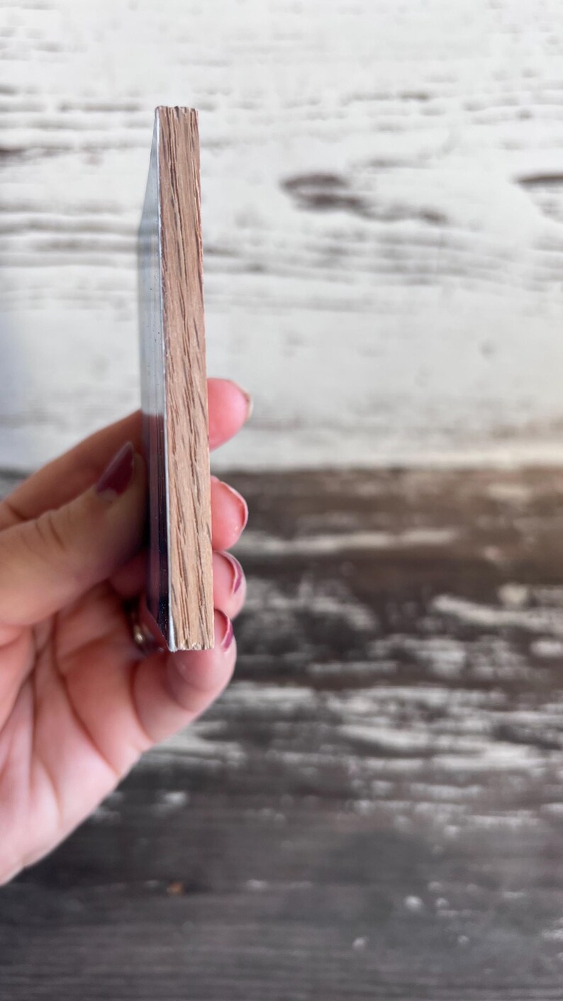 Puede incluir: Primer plano del lateral de una posavasos de madera. La posavasos est&aacute; hecha de madera marr&oacute;n claro con un acabado liso. La posavasos est&aacute; siendo sostenida por una mano.