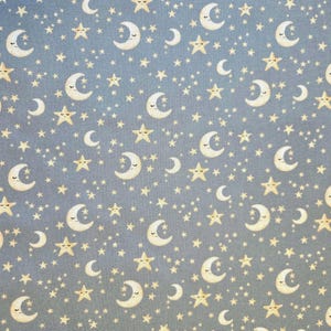May include: A repeating pattern of smiling crescent moons and star shapes in various sizes on a light blue background. The moons and stars are a soft yellow color, creating a whimsical, celestial design.