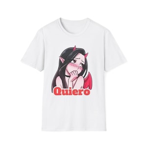 Op de afbeelding: Wit T-shirt met een cartoon illustratie van een vrouwelijk personage met zwart haar, rode hoorns en vleugels. Het personage bloost en het woord "Quiero" is eronder in het rood gedrukt.