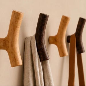 Peut inclure: Quatre patères murales en bois en forme de branches, deux claires et deux foncées. L'une supporte une serviette beige, l'autre une sangle en cuir beige. Les crochets sont fixés sur un mur neutre. Chaque crochet mesure environ 10 cm.