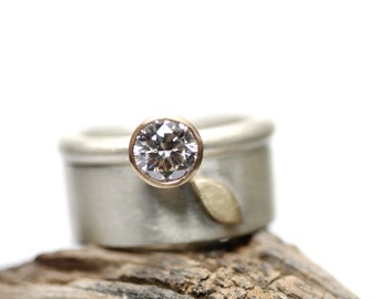 May include: A silver ring with a gold band and a large, clear diamond set in the center.