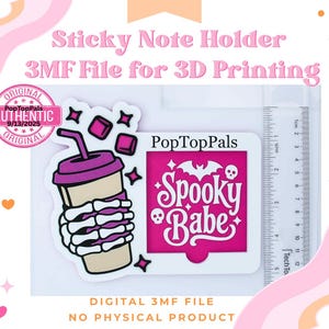 Può includere: File digitale 3MF per la stampa 3D di un porta-post-it. Il design include una mano di scheletro che tiene una bevanda e un quadrato rosa con le parole "Spooky Babe". L'immagine include anche un righello con misure in cm.