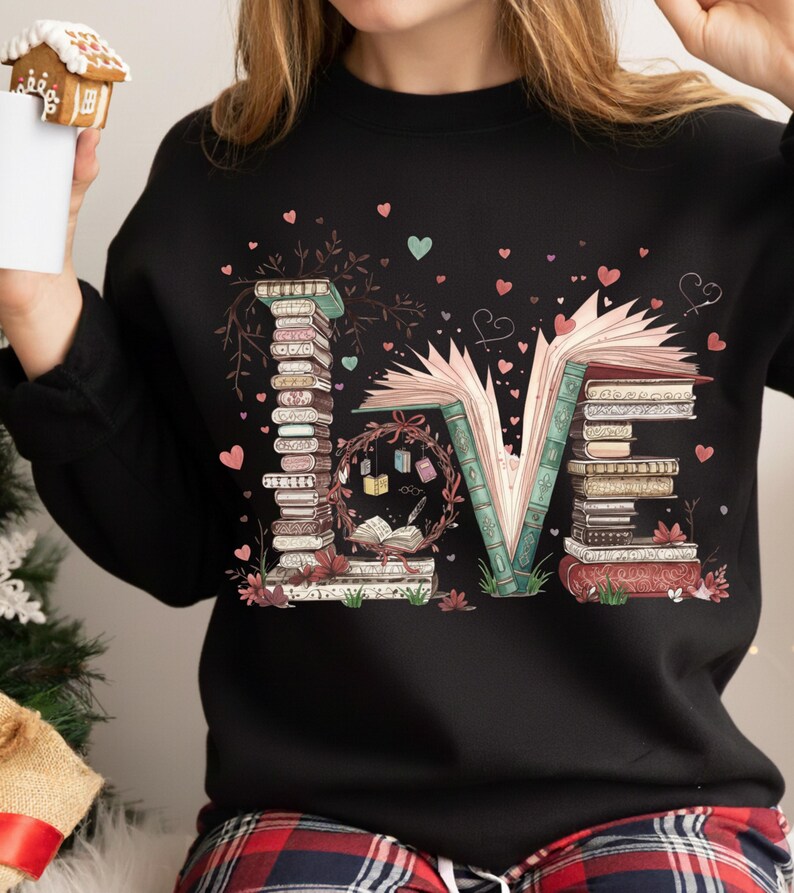 May include: Black sweatshirt with the word "LOVE" spelled out with stacks of books and an open book. The "O" is a wreath with books and hearts. Pink and teal hearts are scattered around the design.