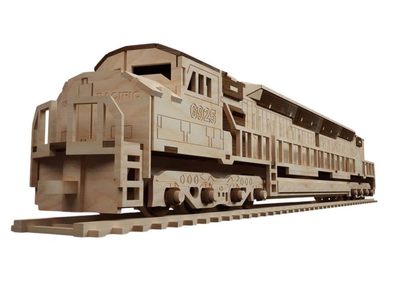 May include: A wooden model of a train engine, featuring the number "6925" and the word "PACIFIC". The model is made of light-colored wood and sits on a wooden track. The design includes detailed cutouts.