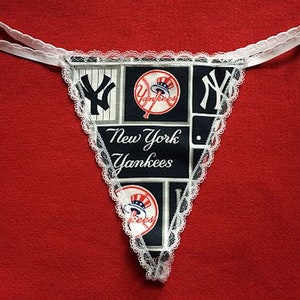 May include: White lace trim lingerie with a black and white New York Yankees themed print. The print features the team logo, a baseball bat, and the words "New York Yankees".