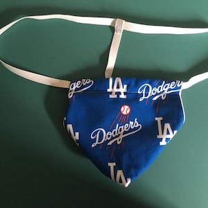 May include: A blue and white fabric pouch with a white elastic strap. The pouch has a repeating pattern of the Los Angeles Dodgers logo and the letters "LA".