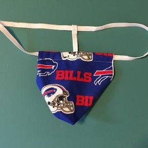 May include: A blue and red fabric jockstrap with a white elastic strap. The fabric has a pattern of Buffalo Bills logos and the word "Bills" repeated.