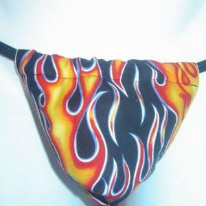 May include: A black and yellow string bikini bottom with a flame pattern.